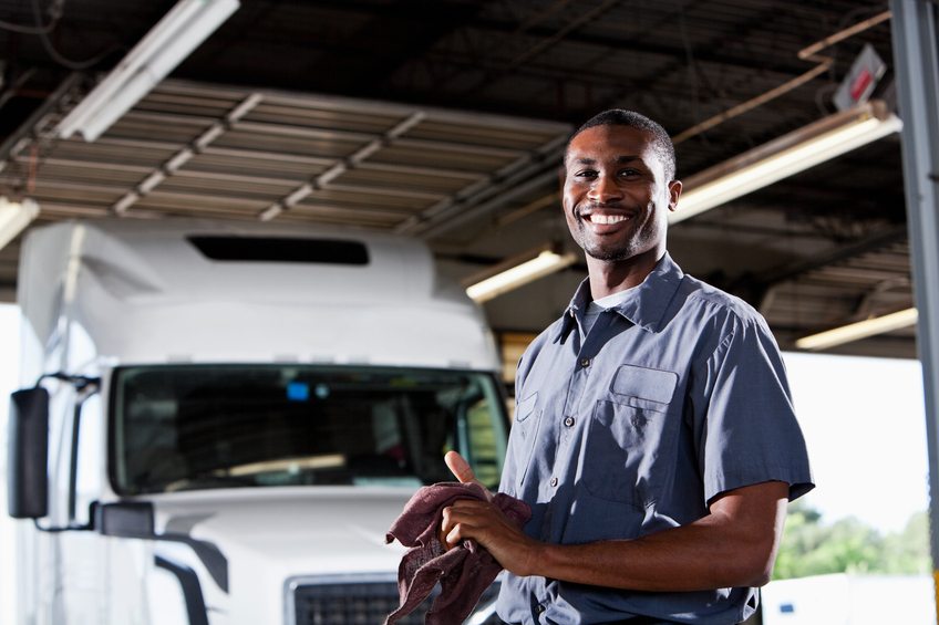 Mechanic in garage with semi-truck African American man (20s) in service garage repairing semi-truck.