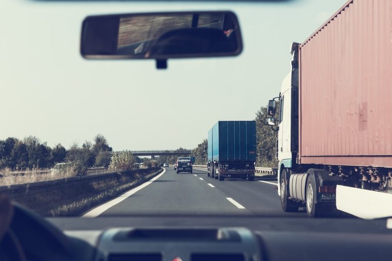 View from inside a vehicle on a highway alongside intermodal shipping container trucks, representing intermodal trucking careers