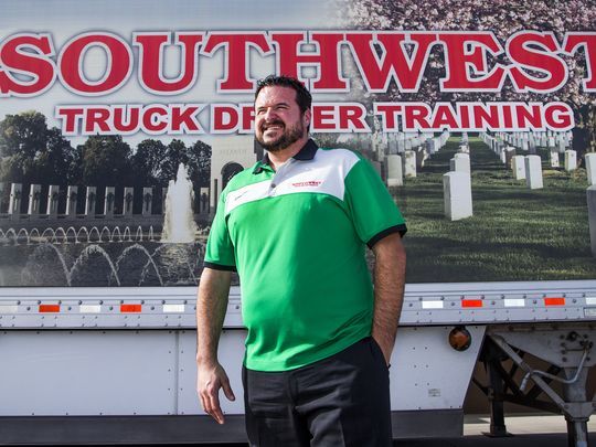 Sean Williams of Southwest Truck Driver Training standing in front of a patriotic memorial-themed company trailer