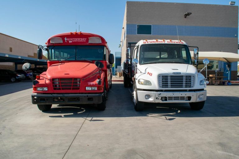 Southwest Truck Driver Training vehicles side by side — a red passenger bus and a white straight truck