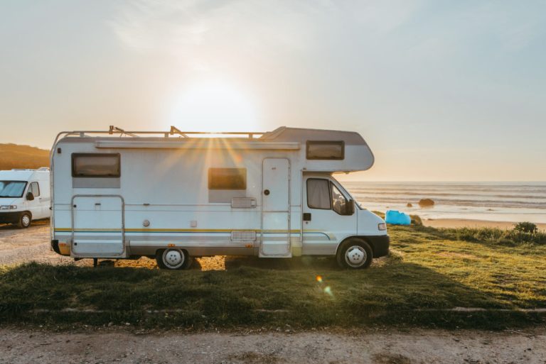 Class C motorhome RV parked at a beachside campsite at sunset
