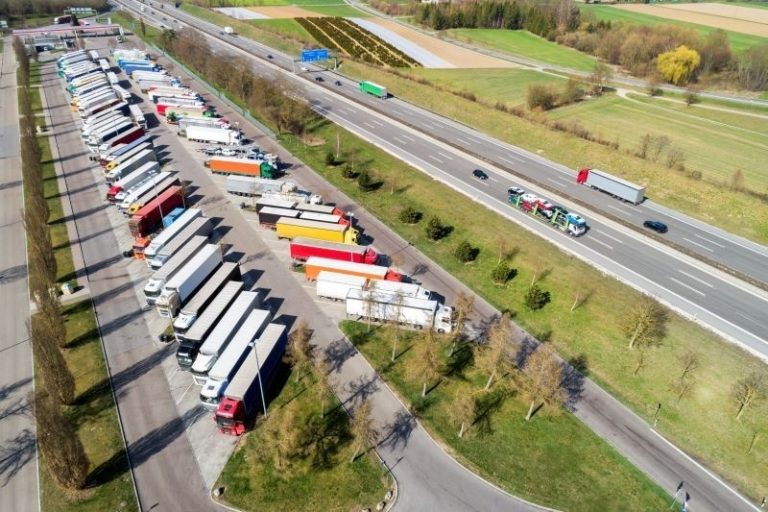 Aerial view of semi-trucks parked at a highway truck stop rest area alongside an interstate