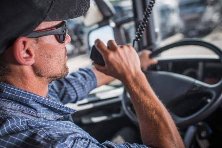 CDL truck driver using a CB radio while behind the wheel of a semi-truck