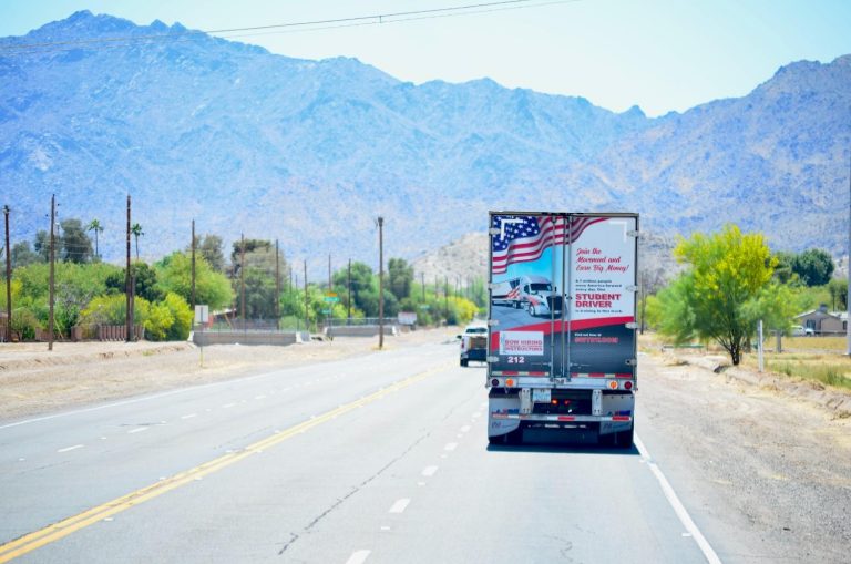 Student driver semi-truck on a Phoenix Arizona highway with desert mountain landscape in the background