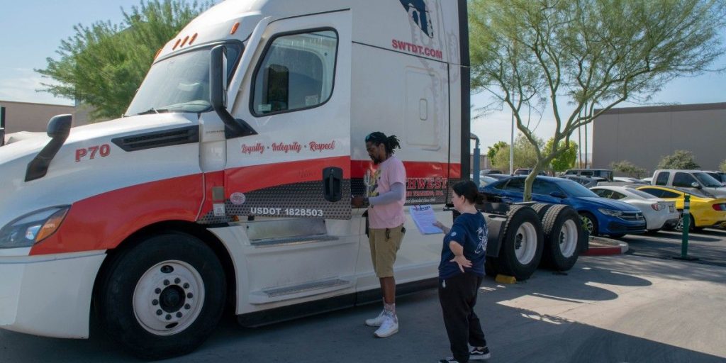 Two CDL students reviewing pre-trip inspection paperwork beside a Southwest Truck Driver Training semi-truck during ELDT-compliant yard training