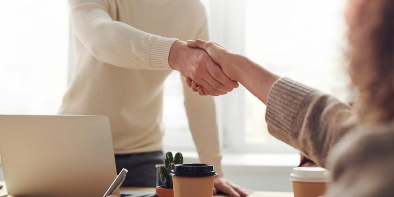 Two people shaking hands across a desk