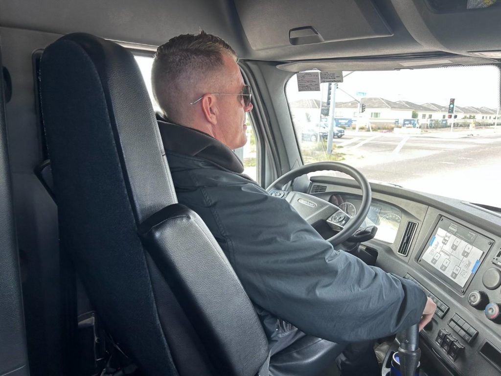 Experienced CDL truck driver behind the wheel navigating city streets in a modern semi-truck cab