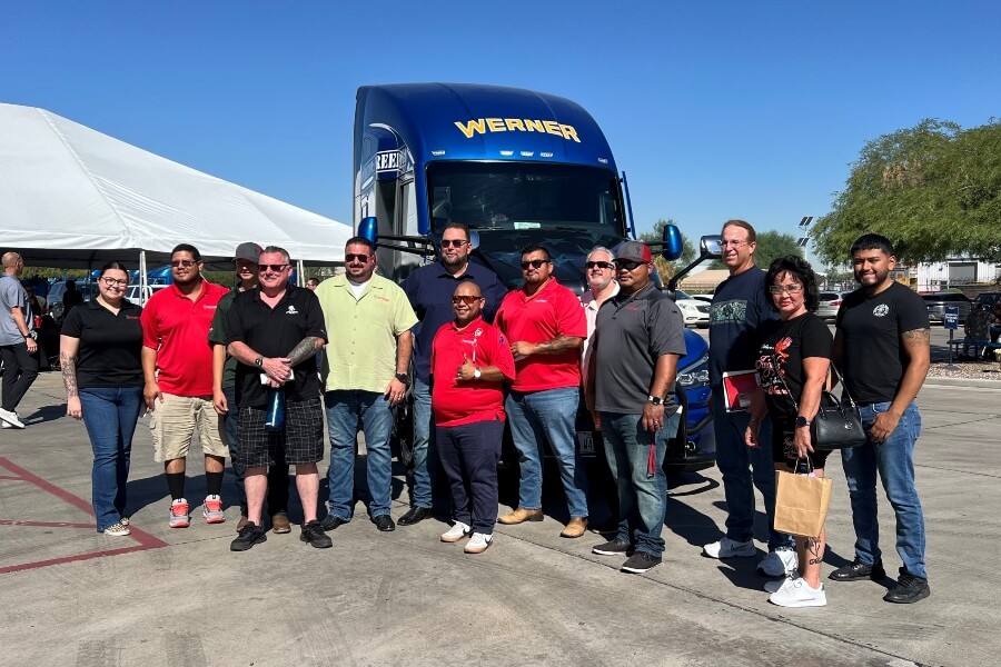 Driver Appreciation Week event attendees from Southwest Truck Driver Training stand with Derek Leathers, Chairman and CEO, Werner Enterprises