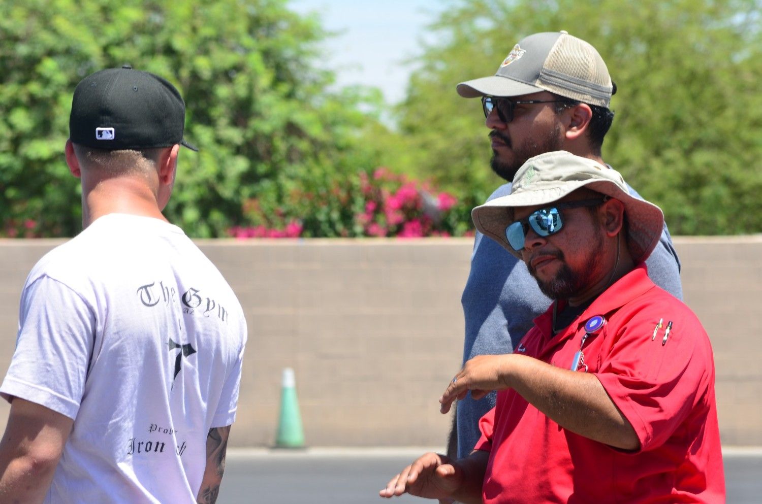 CDL truck driving instructor in red shirt giving hands-on yard training instructions to students