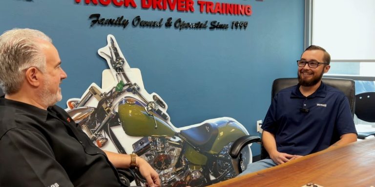 Steve interviewing Dylan at a long table in a Southwest Truck Driver Training conference room