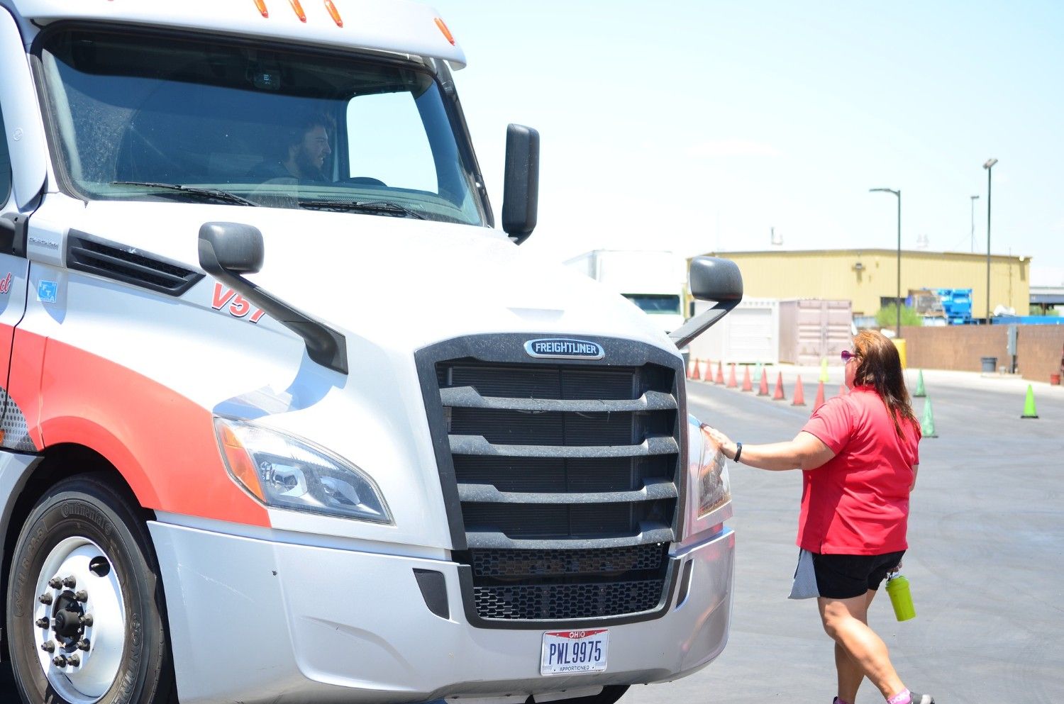 Female CDL instructor spotting a student driver in a semi-truck during yard training