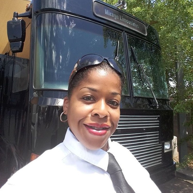 Tasha smiling and standing in front of a black passenger bus