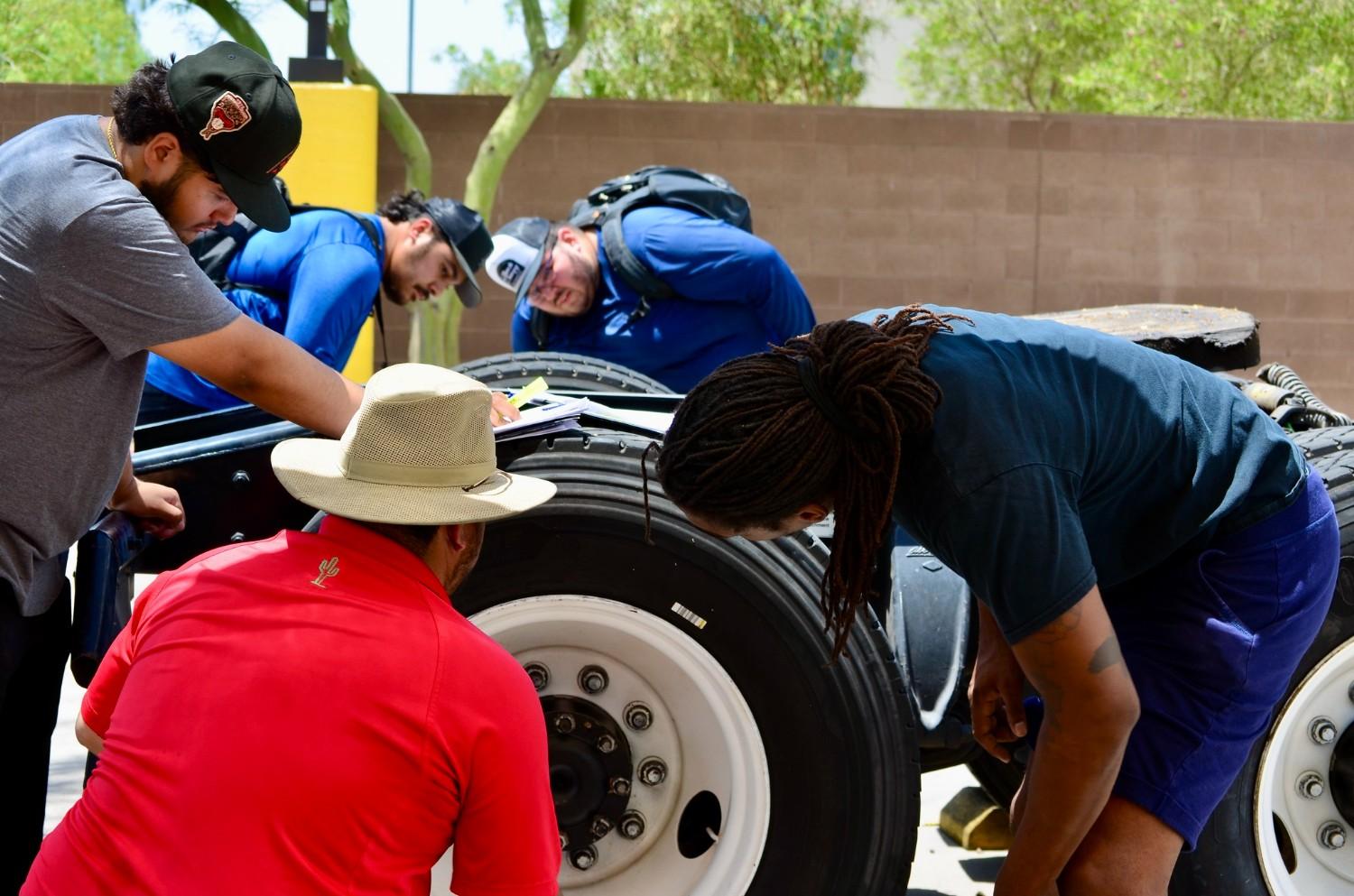 CDL instructor and students performing a pre-trip tire and axle inspection during yard training