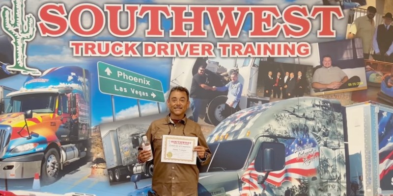 Jimmy holding up his certificate in front of the Southwest background