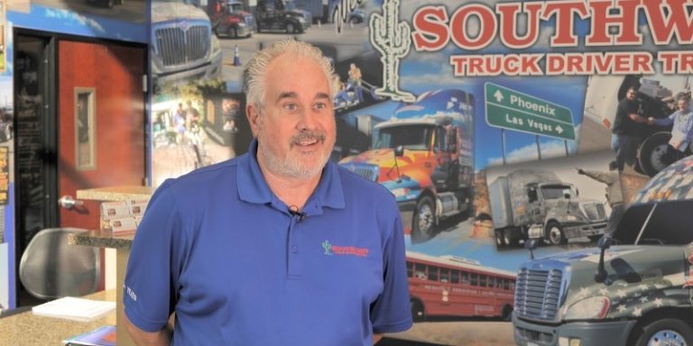 Steve Strong speaks on camera in front of a trucking school backdrop